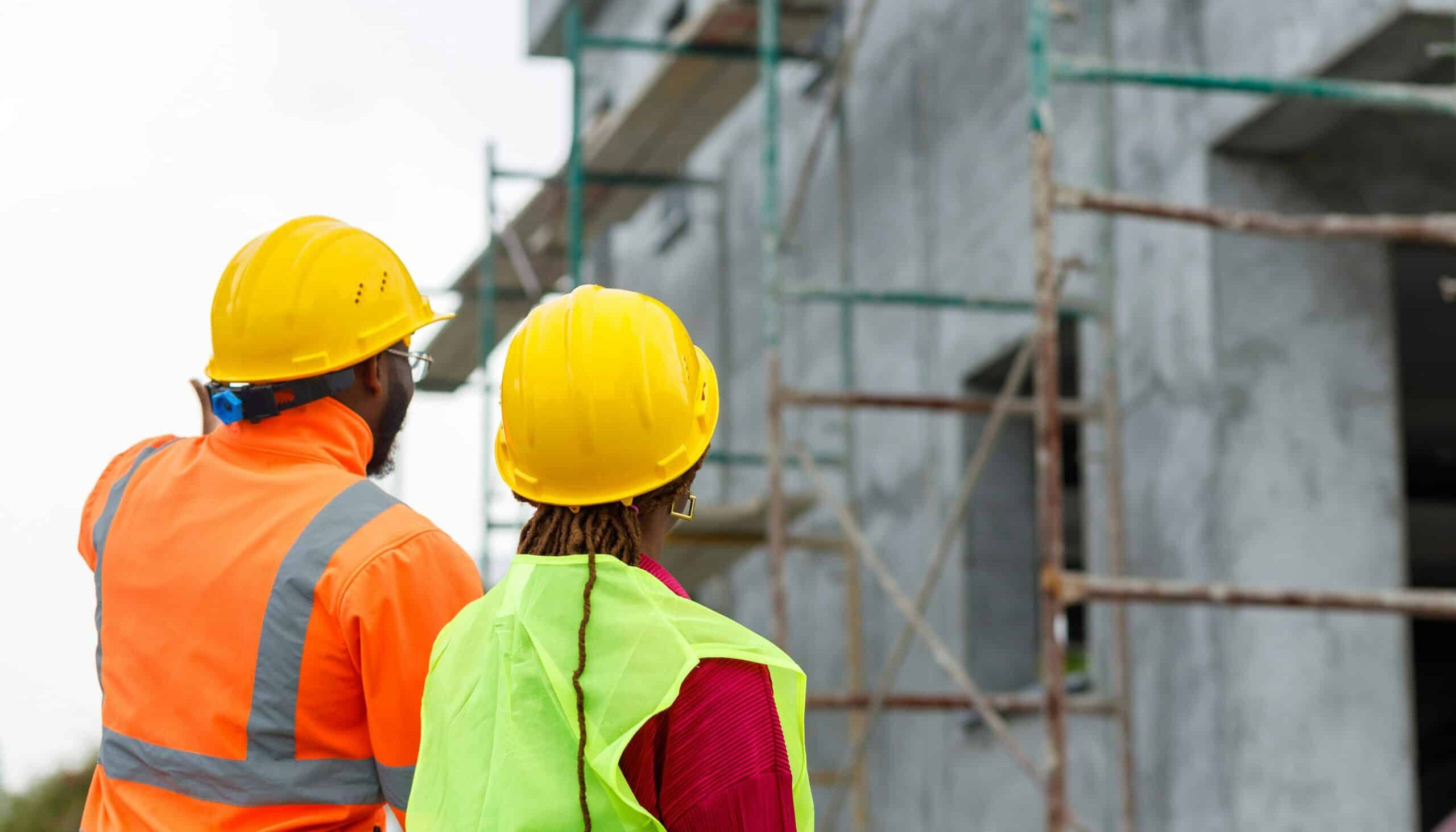 Two construction workers from rear view, looking up at building under construction, representing builder's liens in Vancouver