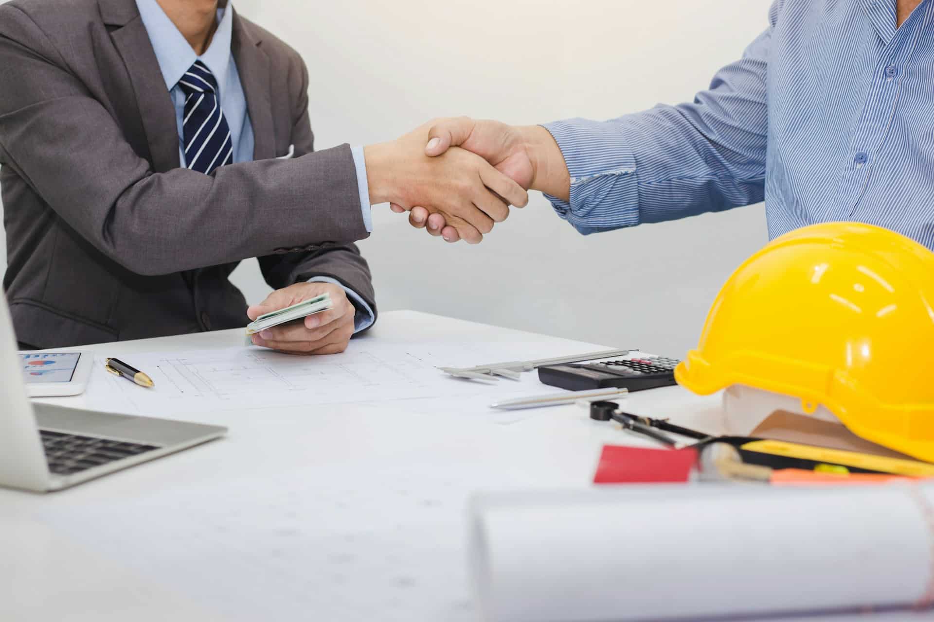 two people shaking hands over a contract with construction gear