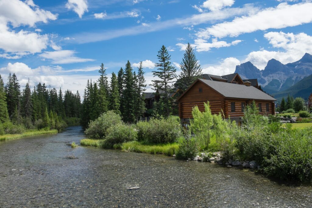 View of a small country house alongside a river with the mountains in the background, representing purchaser's liens and land disputes in BC