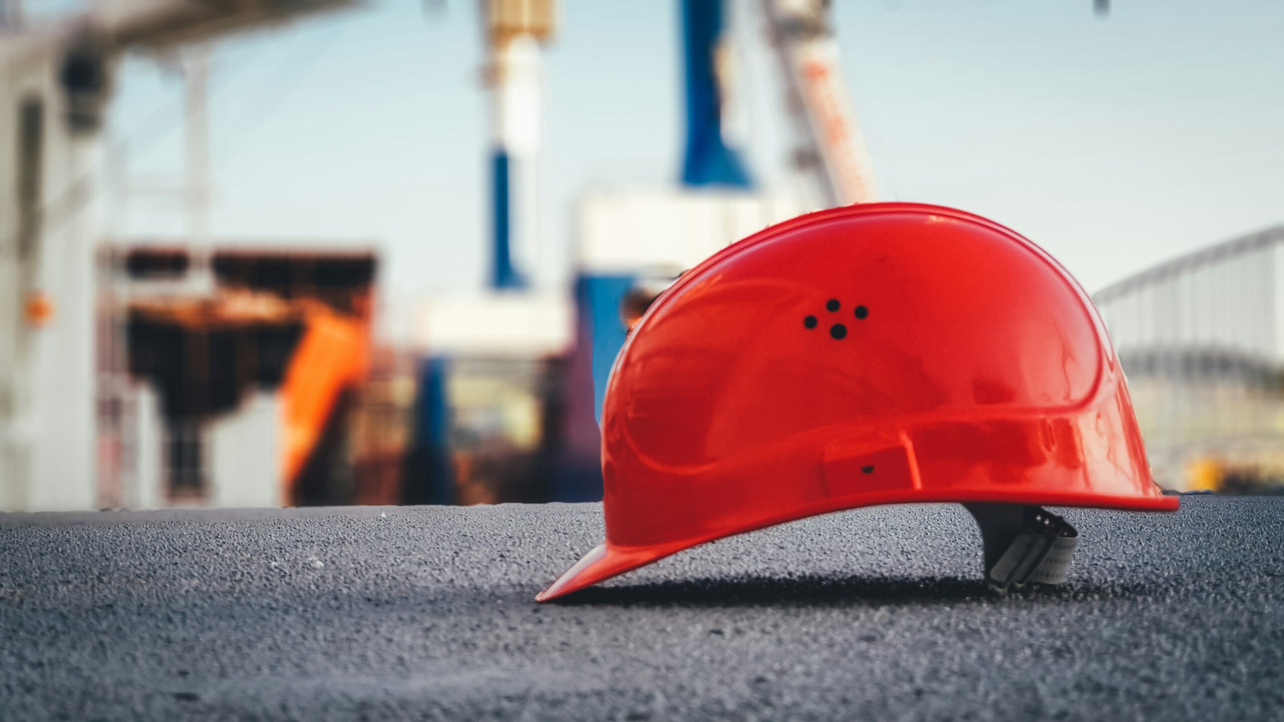 A red hard hat in the foreground with a construction site behind it, representing construction dispute resolution methods in BC.
