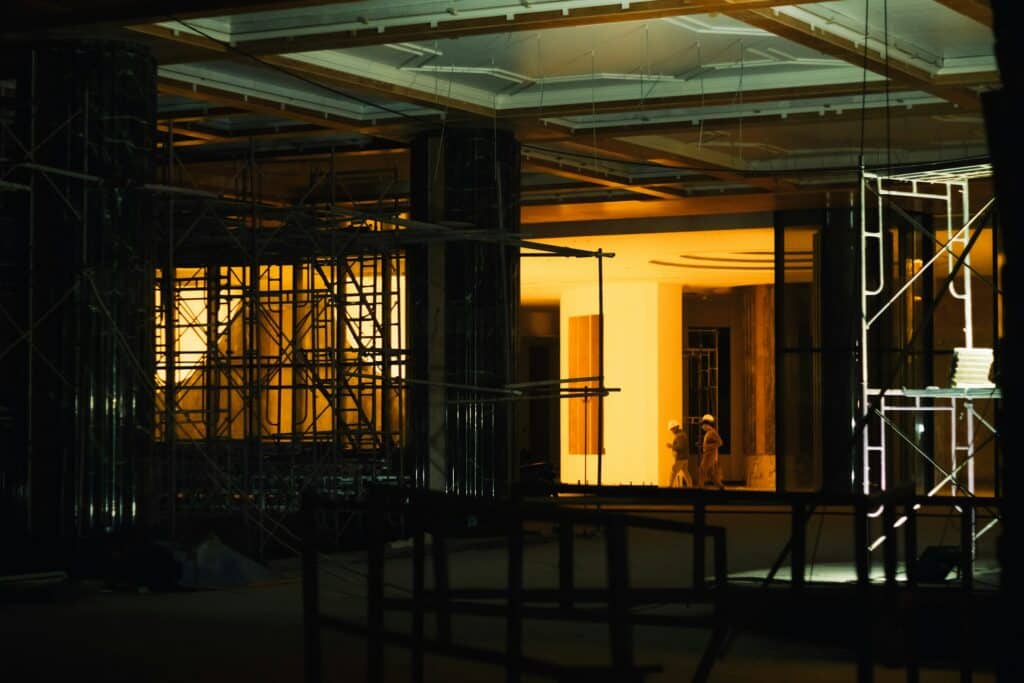 A darkened office building under construction with workers in the background, representing lien bonds and construction projects in BC