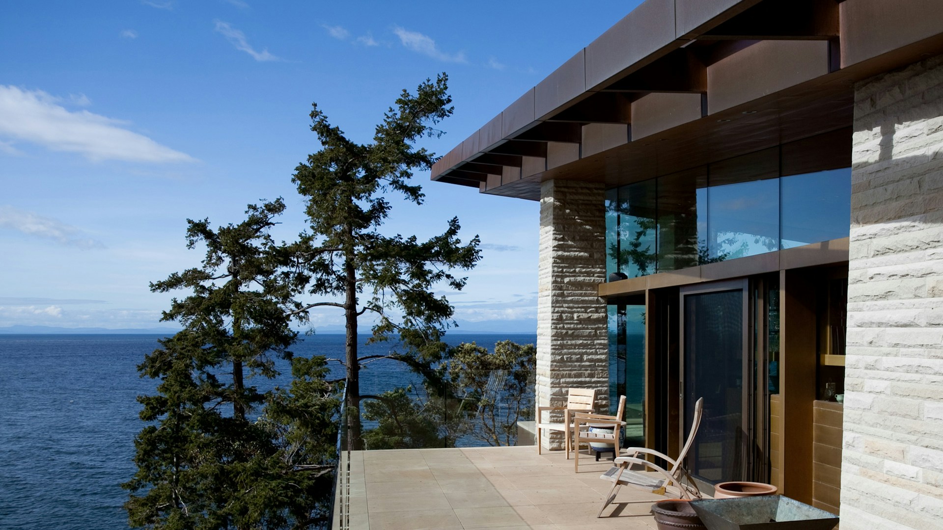 A high-end property's patio with wide glass windows looking out on a lake in British Columbia, representing BC divorce law and inheritances in high-net-worth family law property division.