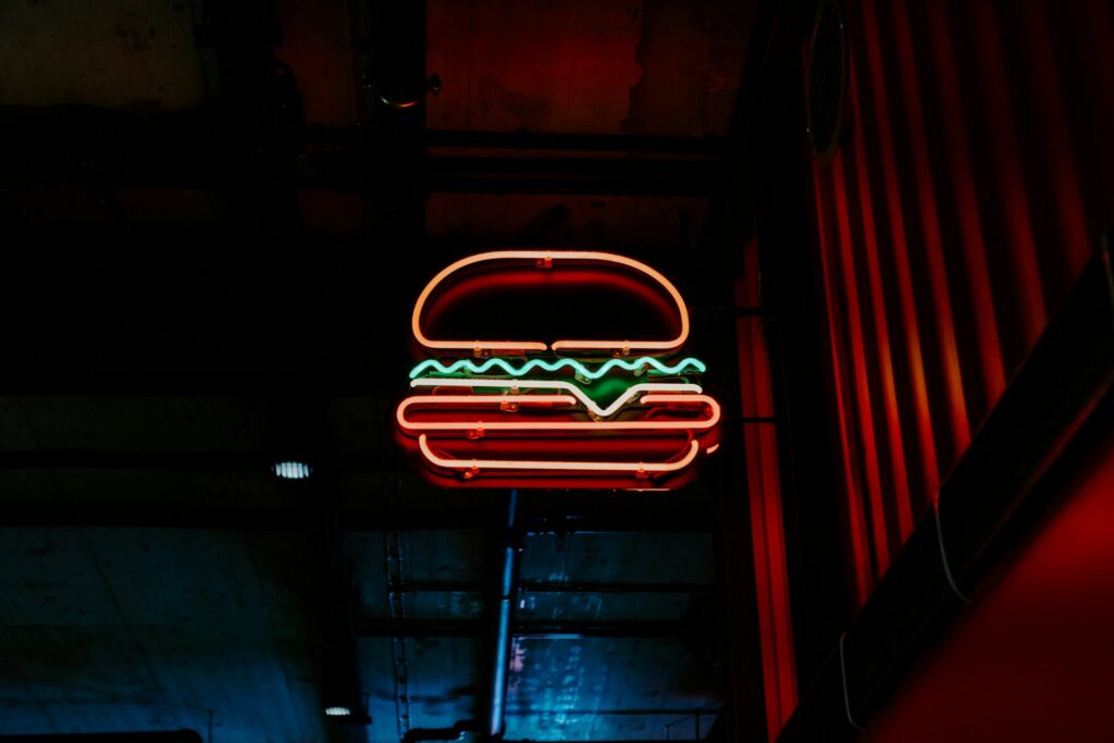 A neon burger affixed to the side of a building, representing commercial rental properties and breaking commercial leases, leading to landlord-tenant disputes in BC.